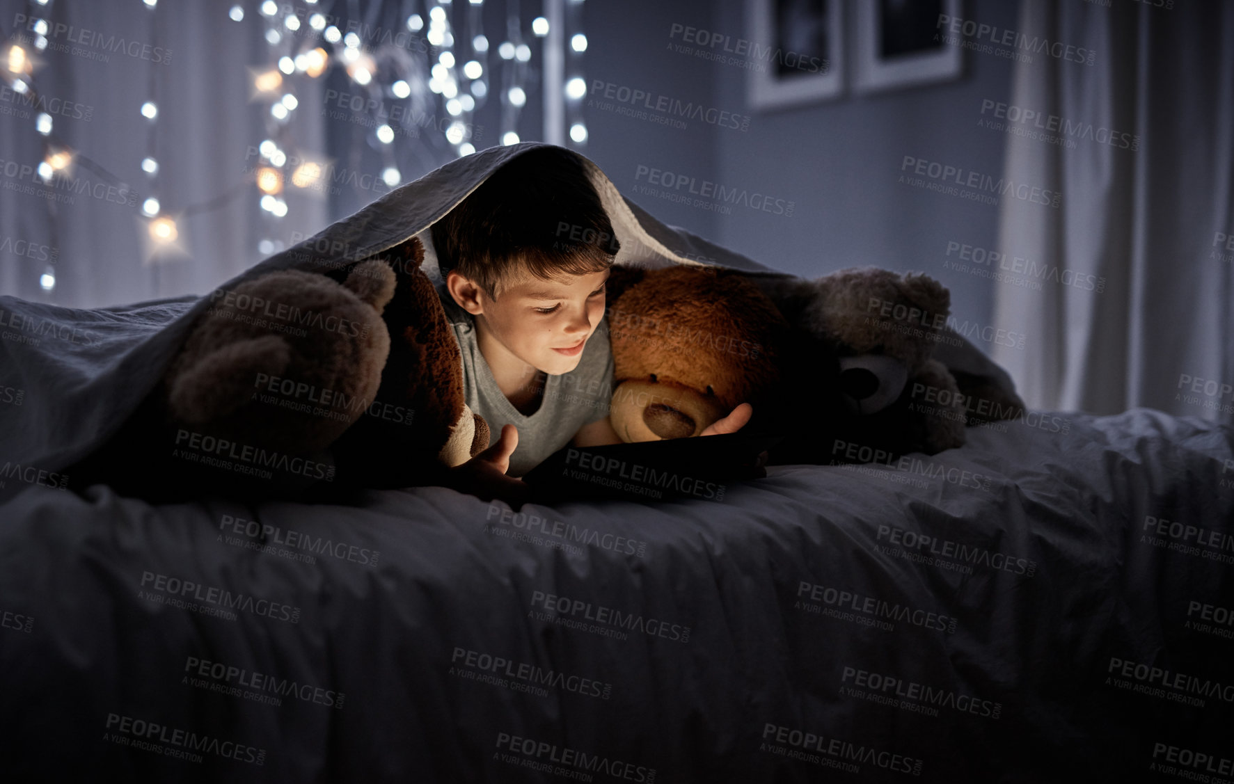 Buy stock photo Shot of an adorable little boy using a digital tablet in bed at night