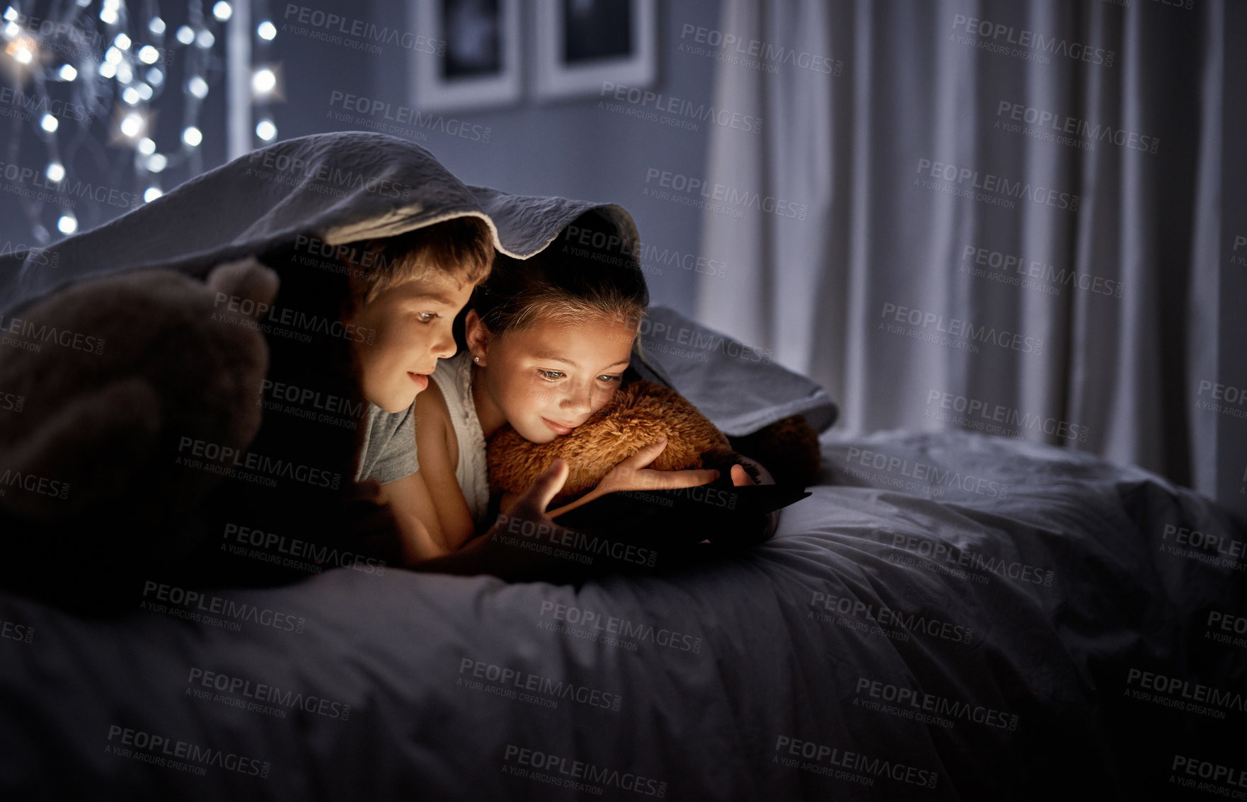 Buy stock photo Shot of two adorable little siblings using a digital tablet together in bed at night