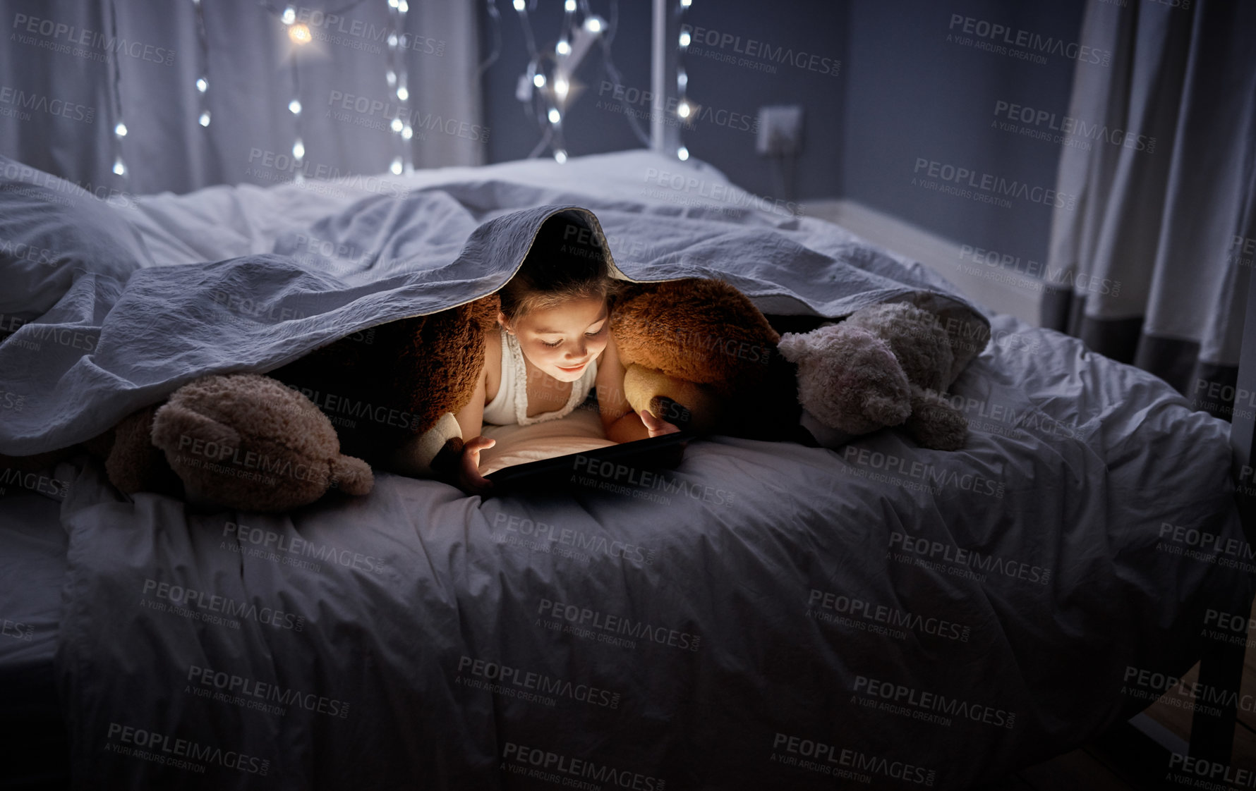 Buy stock photo Shot of an adorable little girl using a digital tablet in bed at night
