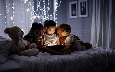 Buy stock photo Shot of an adorable little girl using a digital tablet in bed at night