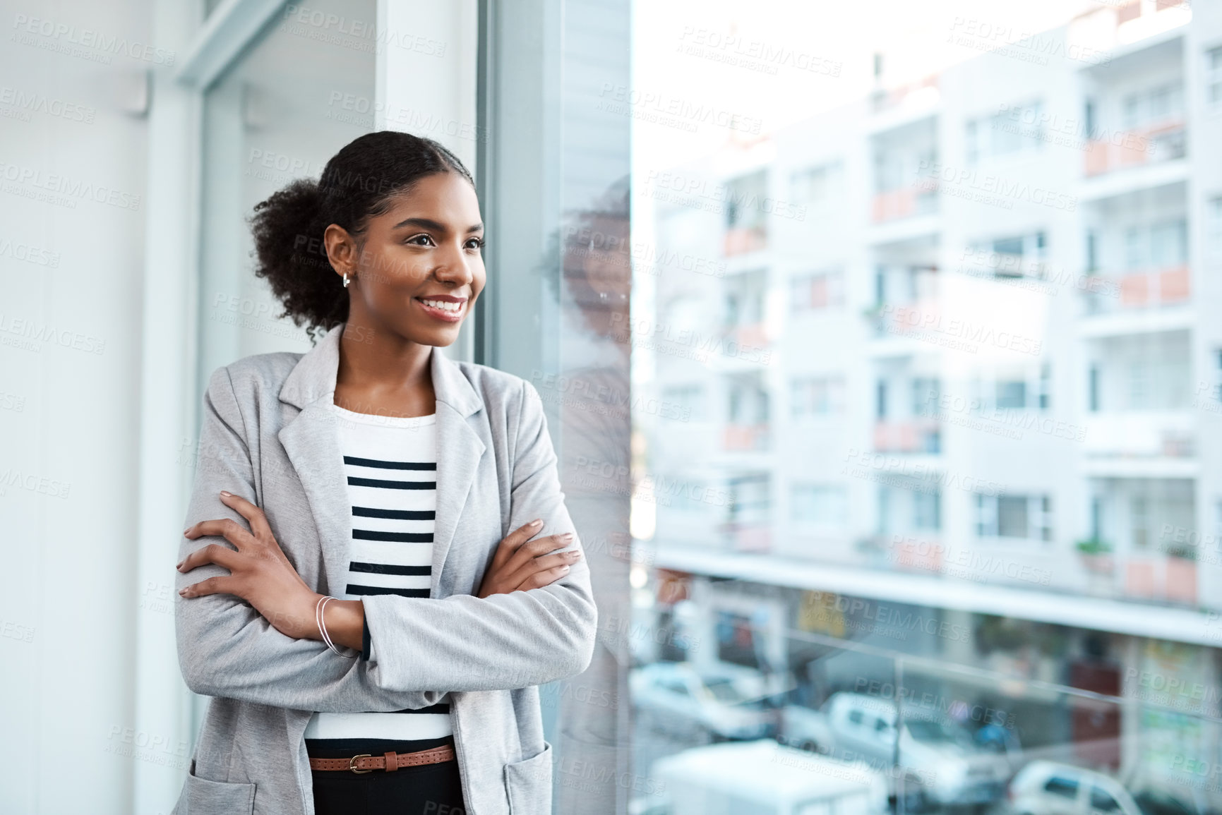 Buy stock photo Young professional businesswoman, smiling while looking out of window of her modern office, thinking in her leadership role. Happy female manager standing with the vision of ambitious motivation