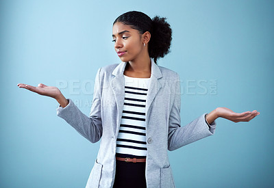 Buy stock photo Confused and serious businesswoman with open hands or palms emoji pose making a difficult decision about future career on blue background. Unsure intern showing balance or choice gesture