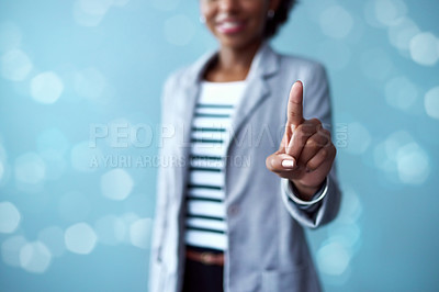 Buy stock photo Cropped studio shot of a young businesswoman touching an interface against a blue background
