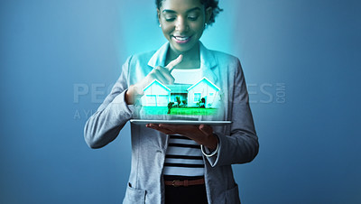Buy stock photo Studio shot of a young businesswoman using a digital tablet with property graphics against a blue background