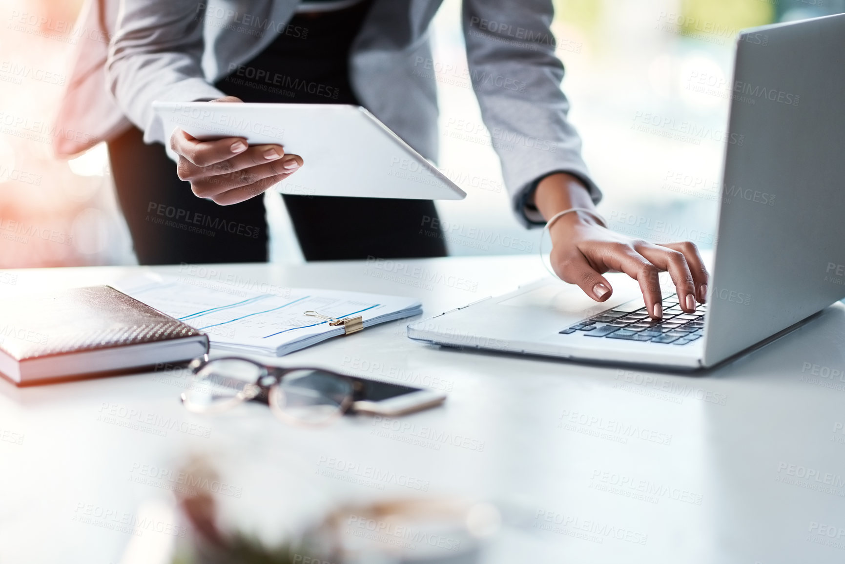 Buy stock photo Business woman working on a laptop and tablet, planning a strategy and browsing the internet for project ideas while working in an office alone at work. Closeup of hands of a corporate executive