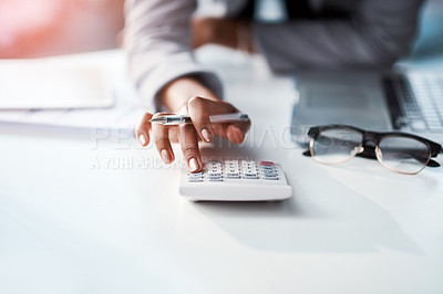 Buy stock photo Cropped shot of a businesswoman using a calculator at her desk in a modern office