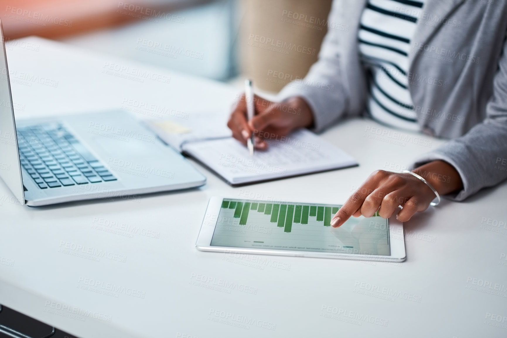 Buy stock photo Shot of an unrecognizable businesswoman using a digital tablet with graphs on it in a modern office