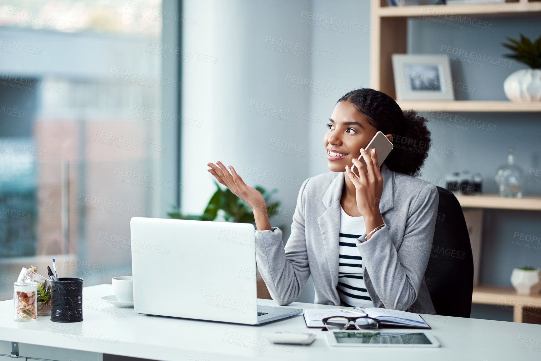 Buy stock photo Young business woman on a phone call talking and planning while sitting alone at a desk on a office computer. Female worker discussing work on her smartphone. An employee embracing modern technology