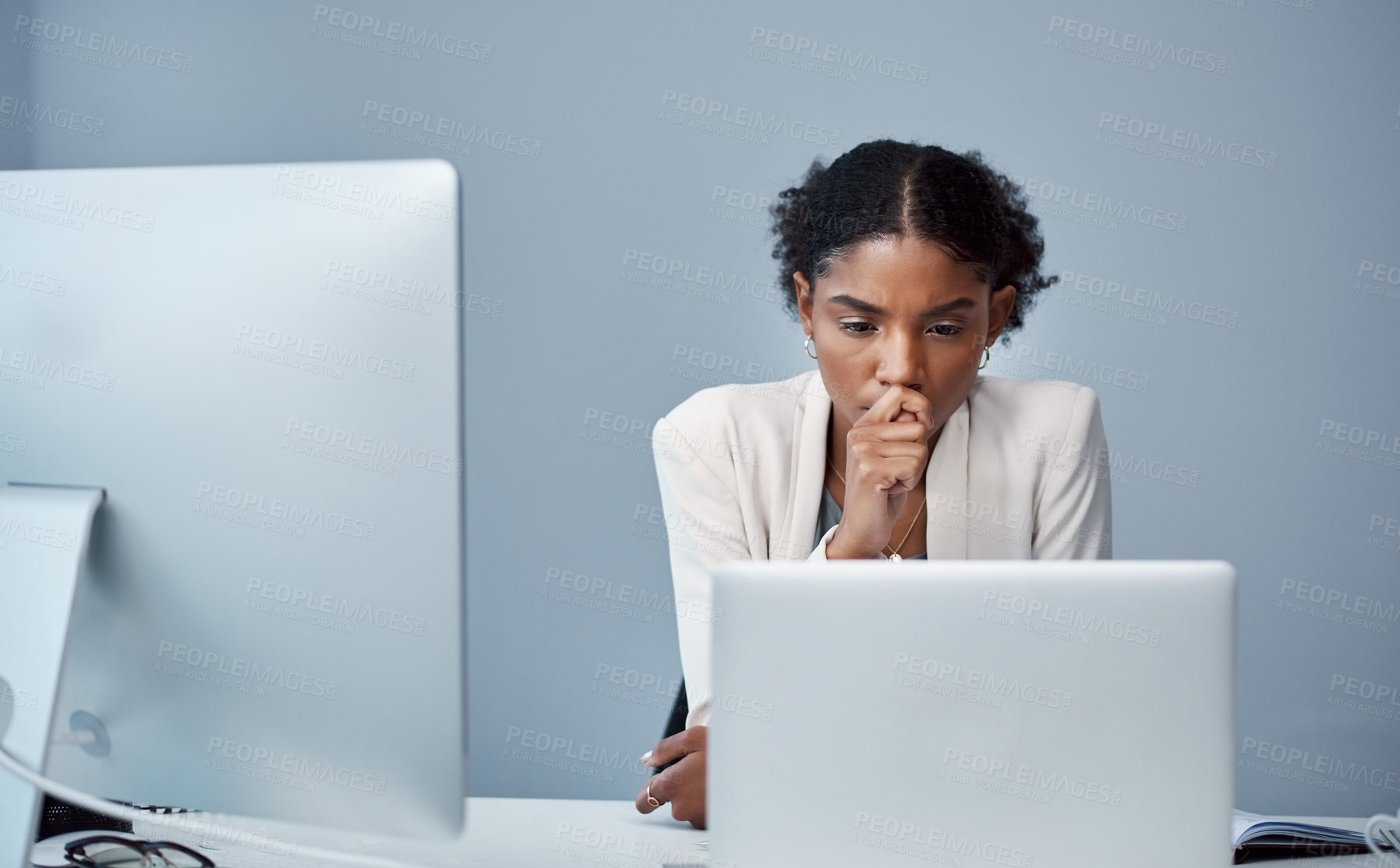 Buy stock photo Shot of a young businesswoman using a laptop and looking anxious at her desk in a modern office