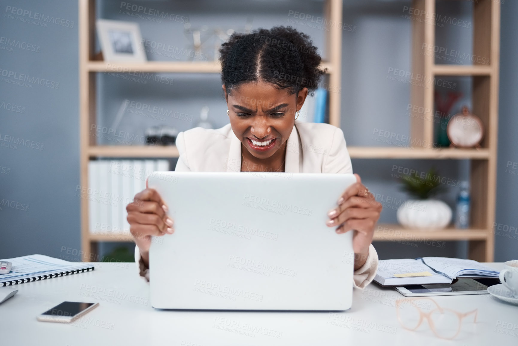 Buy stock photo Frustrated, angry and stressed young business woman on a laptop in a modern office. Female showing anger with technology at the workplace. Lady employee grabbing computer due to slow connection