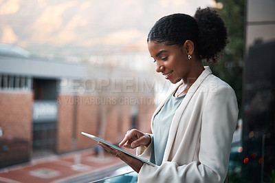 Buy stock photo Shot of a young businesswoman using a digital tablet out on the balcony of a modern office