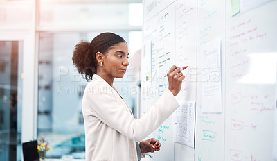 Buy stock photo Young businesswoman planning on a whiteboard in modern office and writing a strategy for the company. Confident female African professional worker brainstorming, preparing for a presentation
