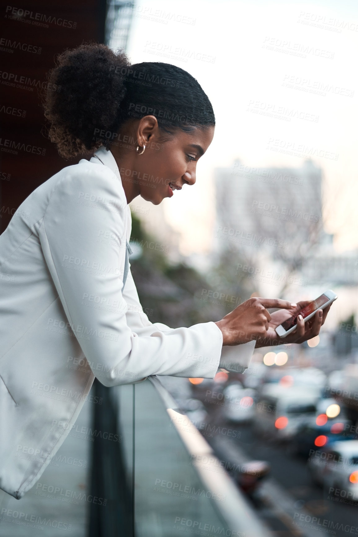 Buy stock photo Relaxed business woman texting on her phone while standing on a balcony on her lunch break. Young corporate female browsing the internet or scrolling on social media after work in a city