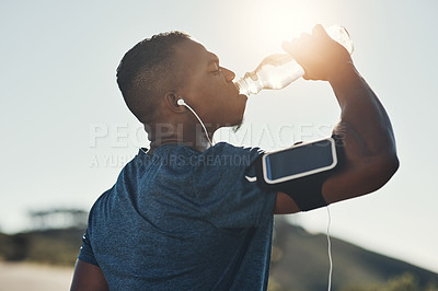 Buy stock photo Black man, drink water and earphones in outdoors for running, thirst and hydrate on sports break. Person, profile and mineral liquid in bottle for nutrition, music and phone app for streaming song