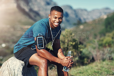 Buy stock photo Cropped shot of handsome young male runner taking a break and drinking water outdoors