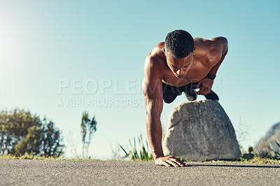 Buy stock photo Shot of a handsome young man doing push ups outdoors