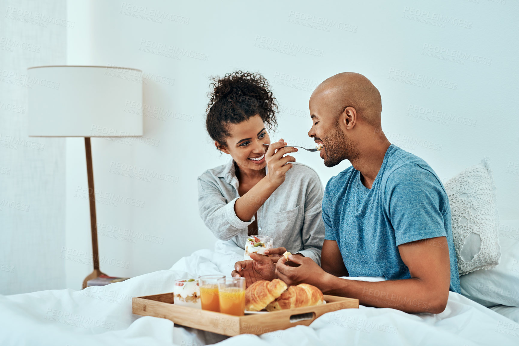 Buy stock photo Cropped shot of an affectionate young couple having breakfast in bed