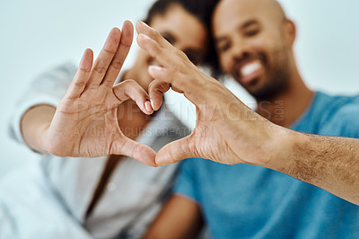 Buy stock photo Defocused shot of a couple forming a heart with their hands