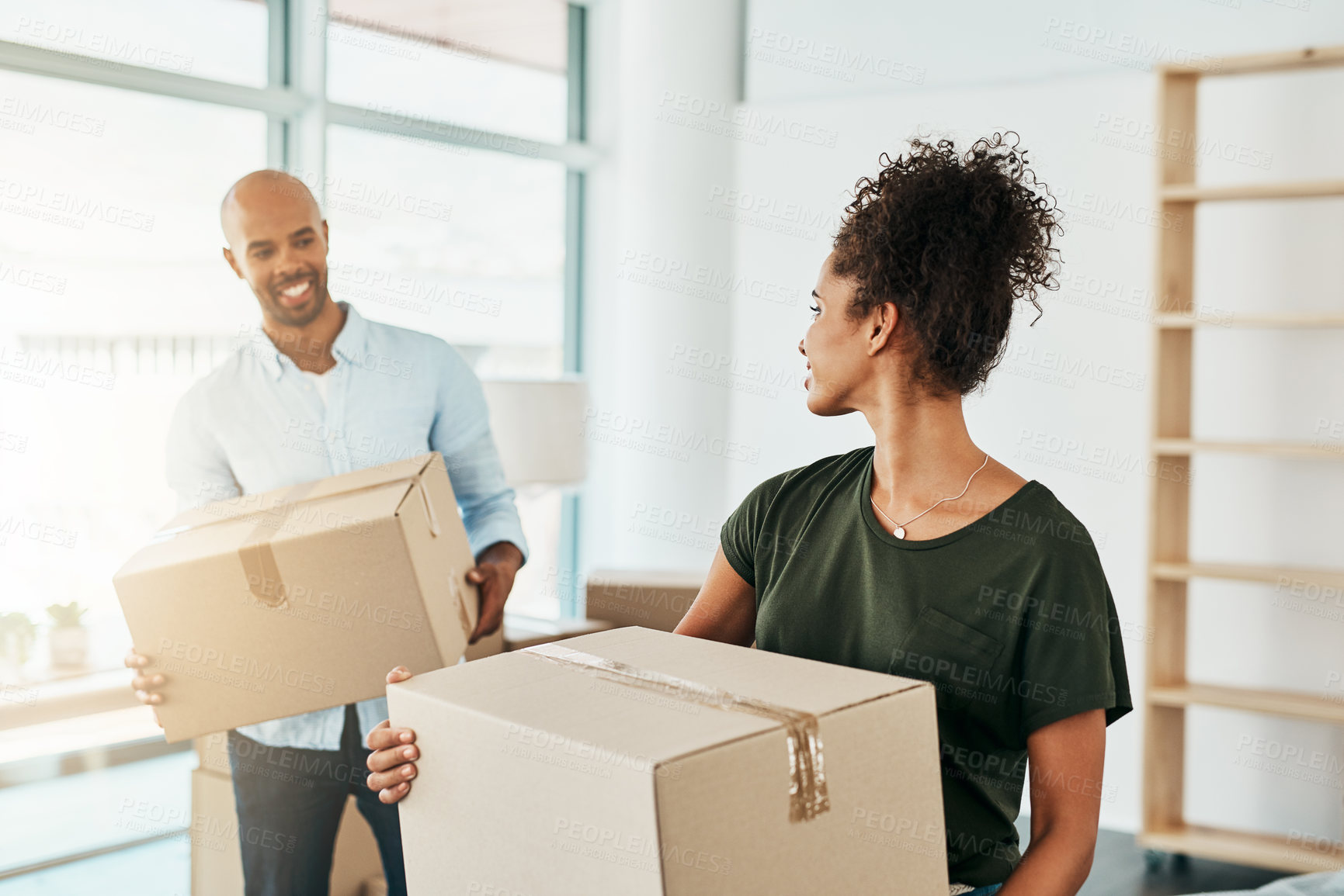 Buy stock photo Shot of a young couple carrying boxes while moving house