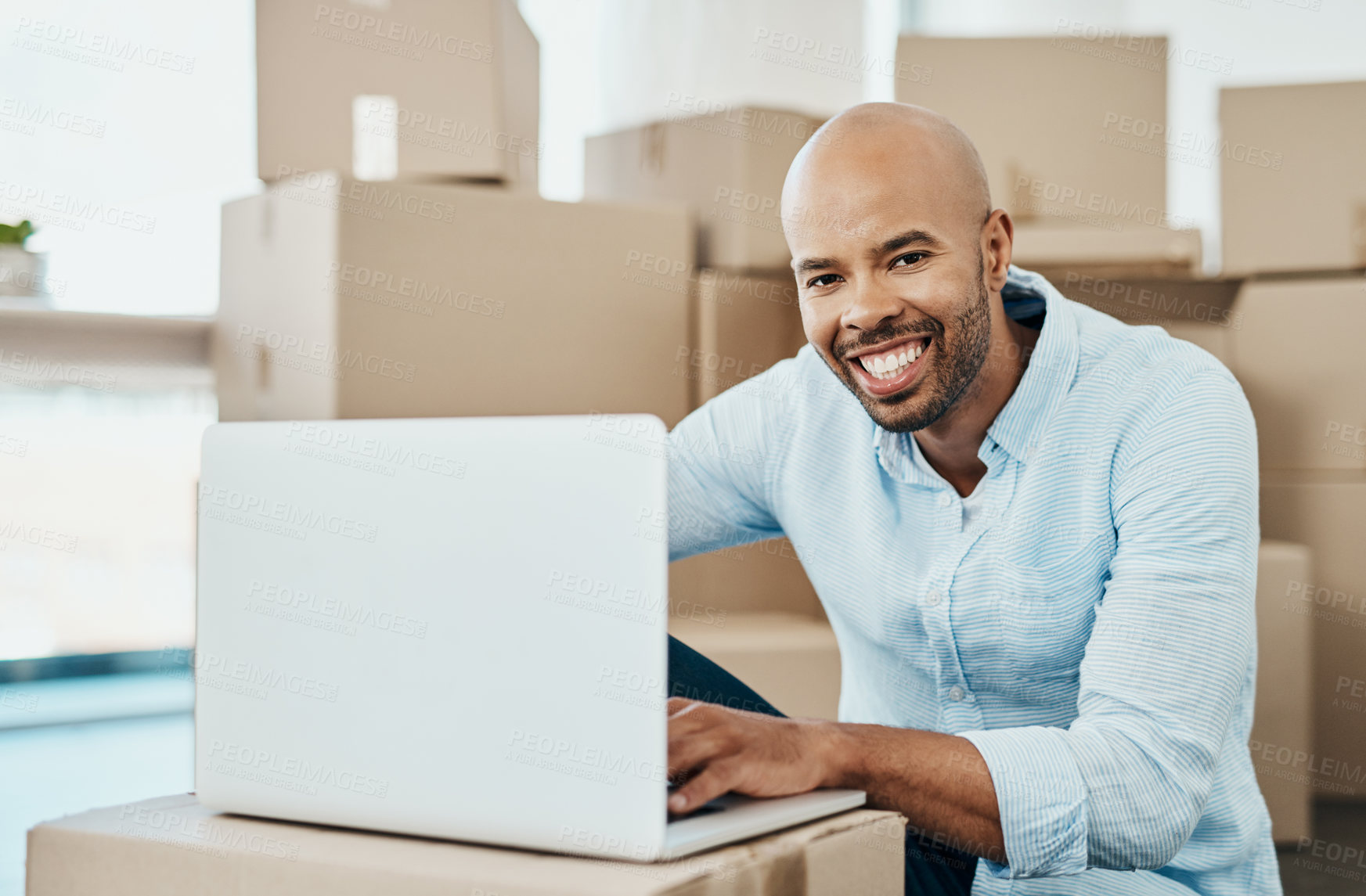 Buy stock photo Portrait of a young man using a laptop while moving house