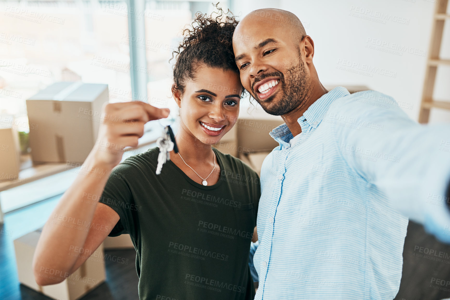 Buy stock photo Portrait of a young couple taking a selfie while holding the keys to their new home