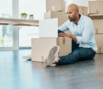 Buy stock photo Shot of a young man using a laptop while moving house
