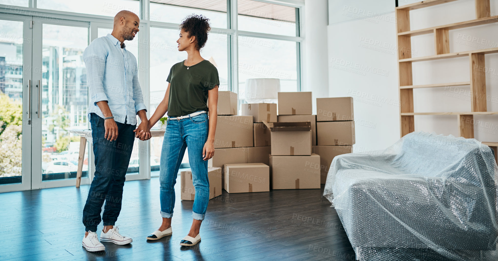 Buy stock photo Shot of a young couple holding hands while moving house
