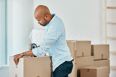 Buy stock photo Shot young man sealing a box while moving house