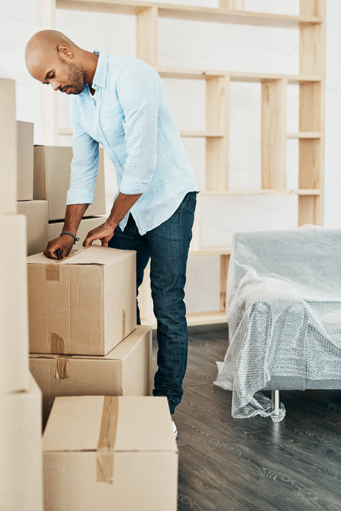 Buy stock photo Shot of a young man unpacking boxes while moving house