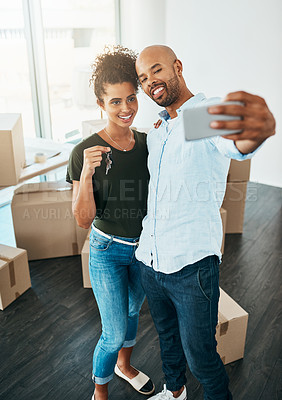 Buy stock photo Shot of a young couple taking a selfie while holding the keys to their new home