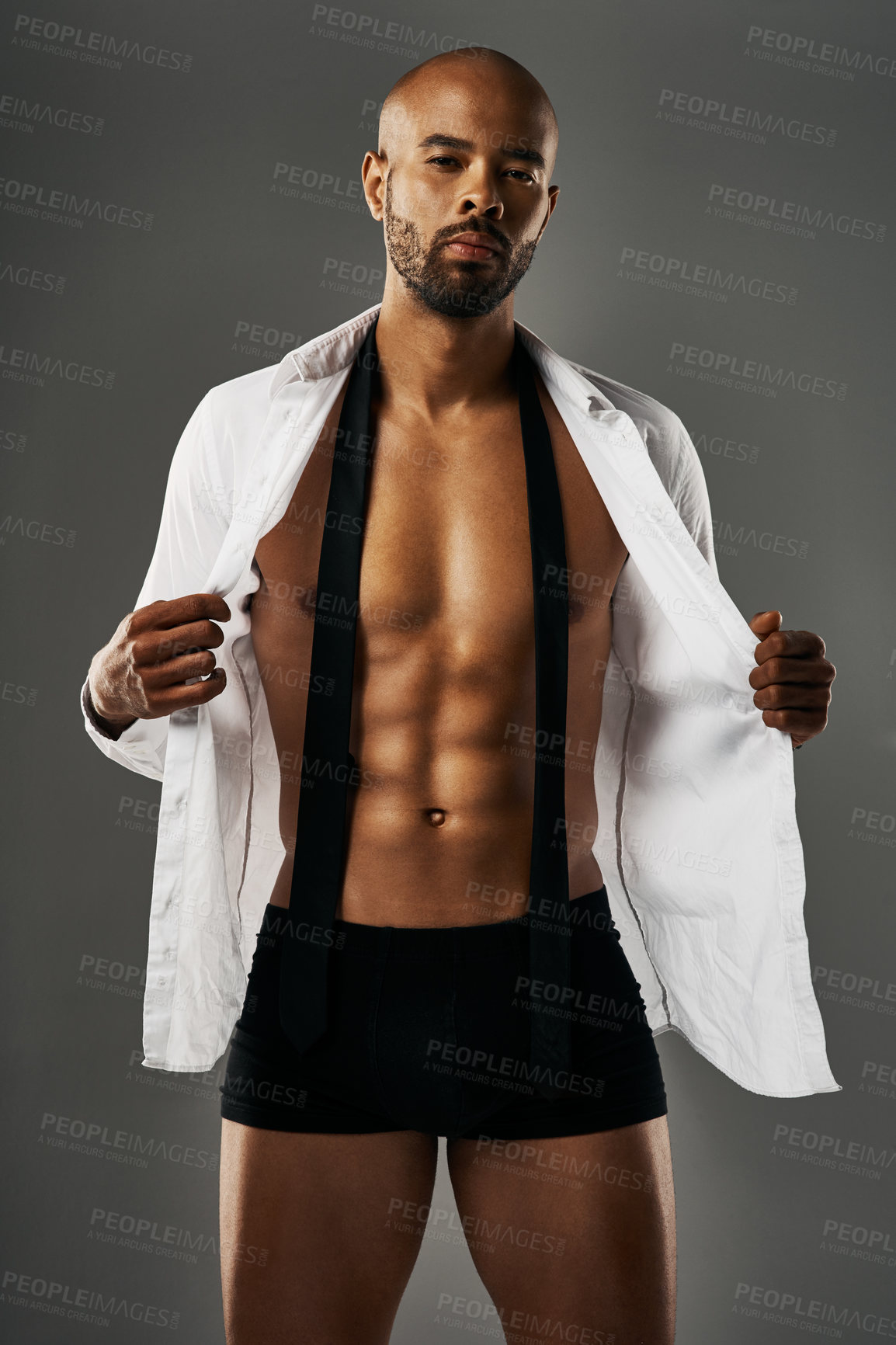 Buy stock photo Studio portrait of a sexy young man showing off his abs against a gray background