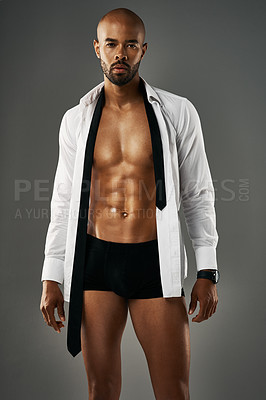 Buy stock photo Studio portrait of a sexy young man showing off his abs against a gray background