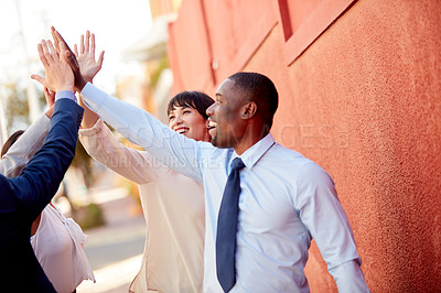 Buy stock photo Shot of a group of businesspeople high fiving together outdoors
