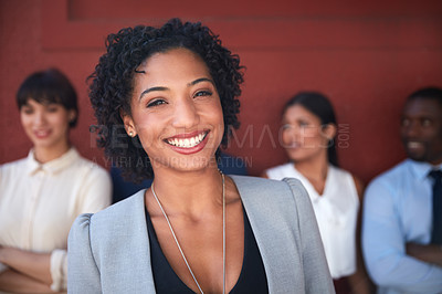 Buy stock photo Portrait of a young businesswoman standing outside with her colleagues in the background