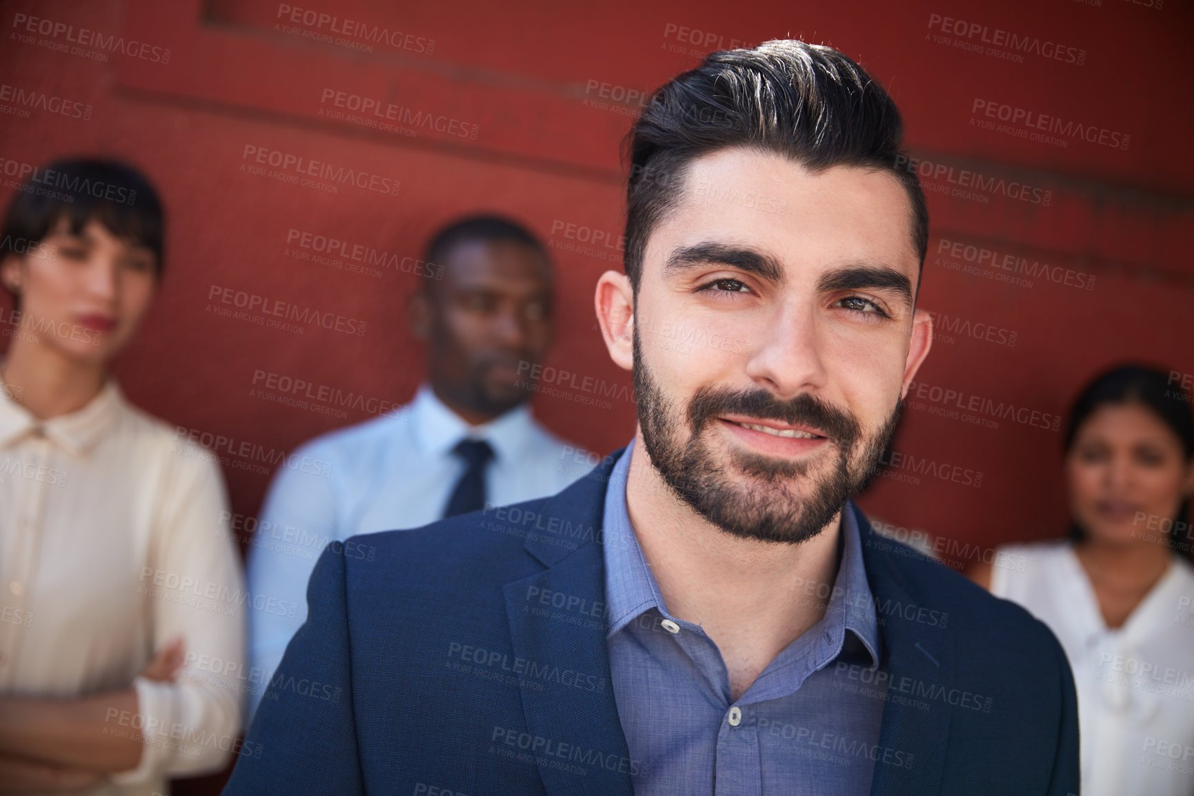 Buy stock photo Portrait of a young businessman standing outside with his colleagues in the background