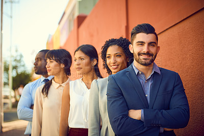 Buy stock photo Portrait of a young businessman standing outside with his colleagues in the background