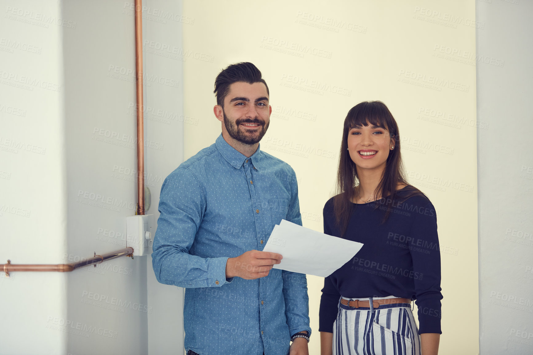 Buy stock photo Portrait of a young businessman and businesswoman going over paperwork in a modern office