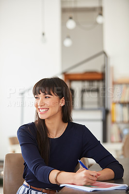 Buy stock photo Shot of a young businesswoman working through paperwork her desk in a modern office