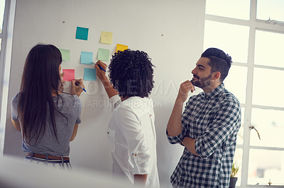 Buy stock photo Shot of a group of businesspeople having a brainstorming session on a wall in a modern office