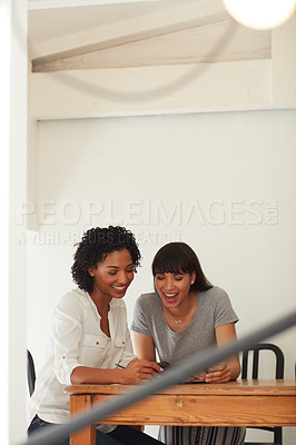 Buy stock photo Shot of two young businesswomen using a mobile phone together in a modern office