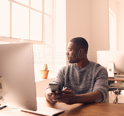 Buy stock photo Shot of a young businessman using a mobile phone at his desk in a modern office