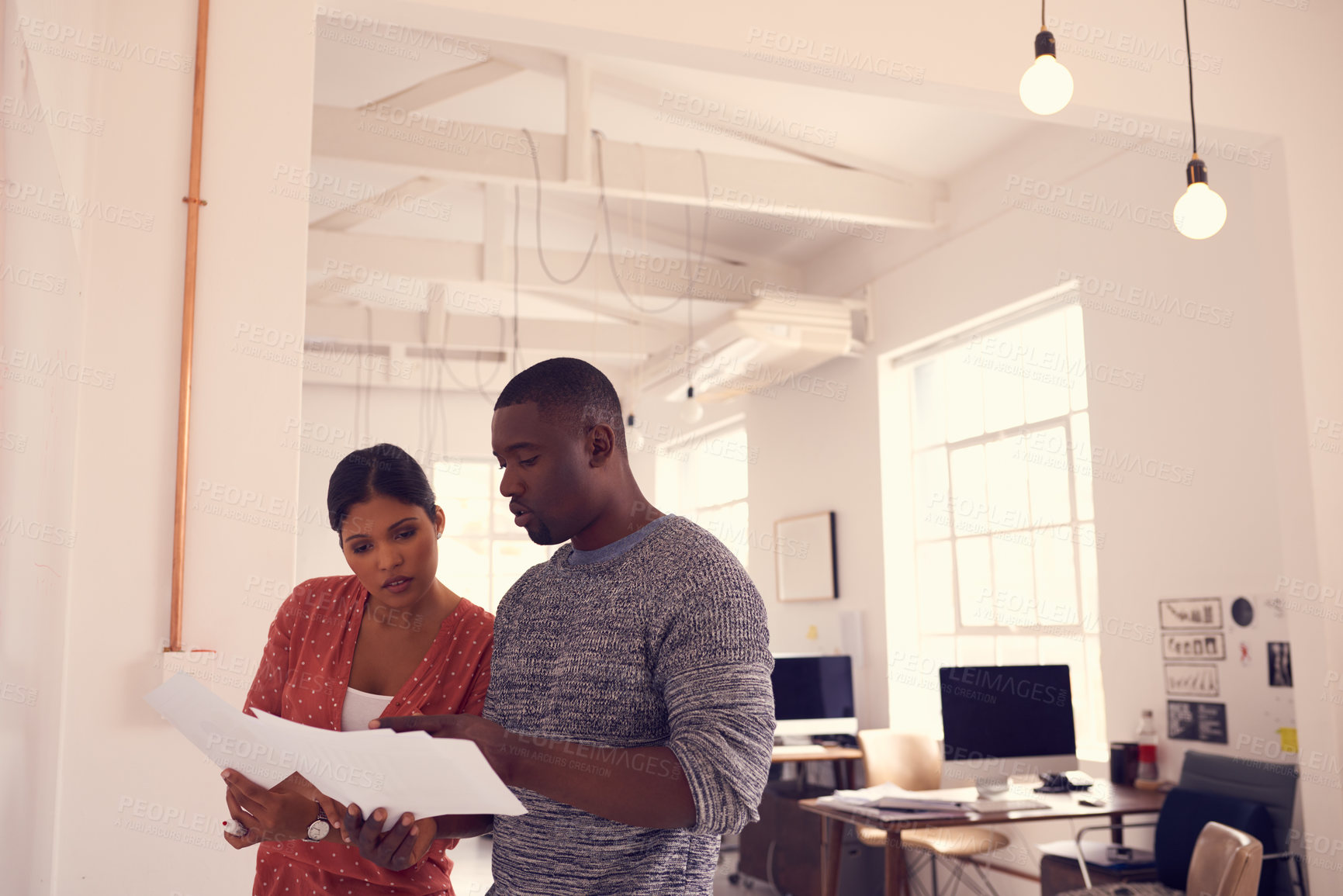 Buy stock photo Shot of a young businessman and businesswoman discussing paperwork in a modern office