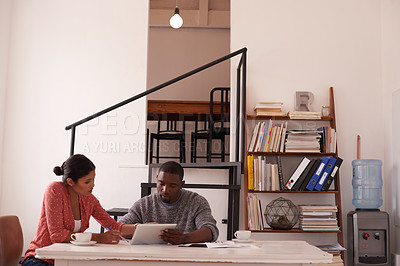 Buy stock photo Shot of a young businessman and businesswoman using a digital tablet while discussing paperwork in a modern office