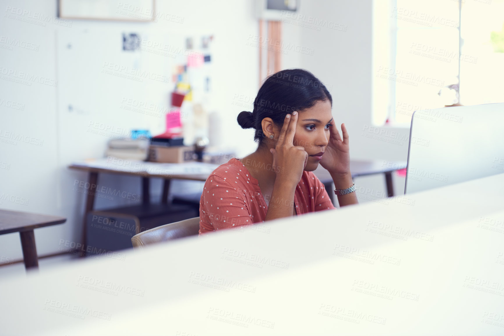 Buy stock photo Shot of a young businesswoman looking stressed while using a computer in a modern office