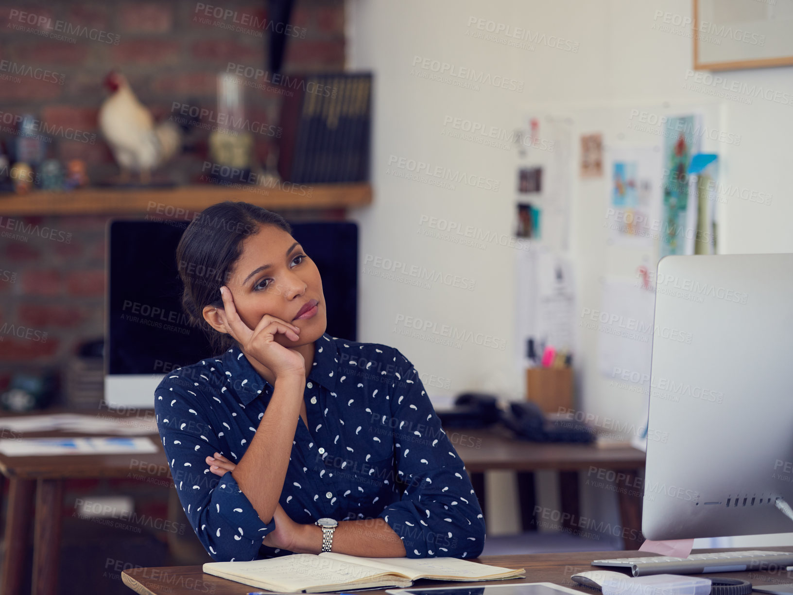Buy stock photo Shot of a young businesswoman looking thoughtful while working at her desk in a modern office