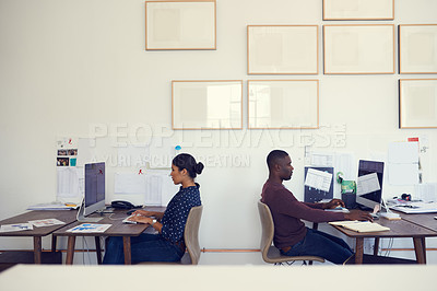 Buy stock photo Shot of a young businessman and businesswoman using their computers in a modern office
