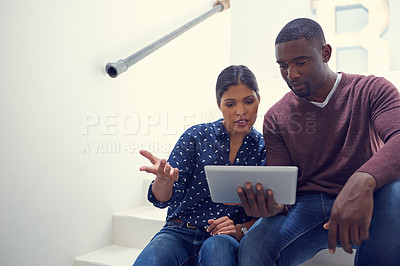 Buy stock photo Shot of a young businessman and businesswoman using a digital tablet together in a modern office