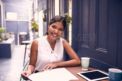 Buy stock photo Portrait of a young businesswoman going through paperwork in an office