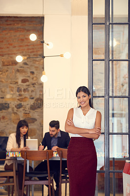 Buy stock photo Portrait of a young businesswoman standing in an office with her colleagues in the background