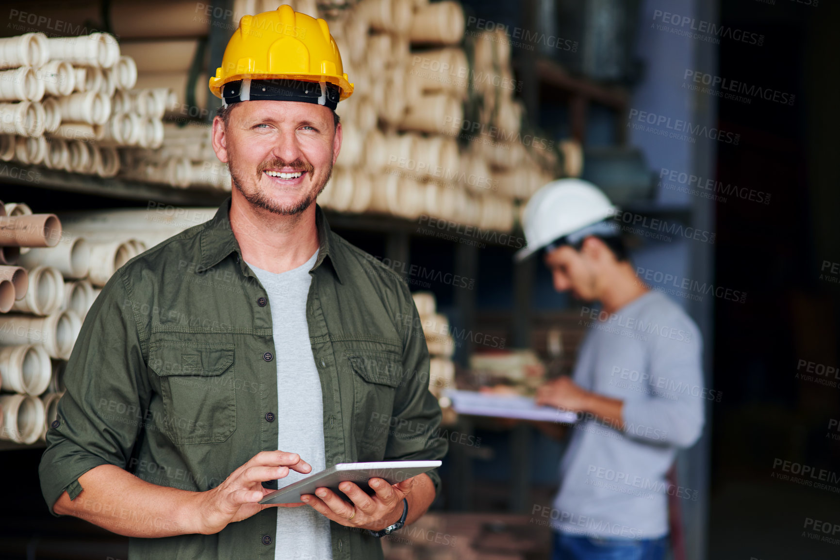 Buy stock photo Cropped portrait of a handsome mature construction worker using his tablet while standing in an industrial warehouse